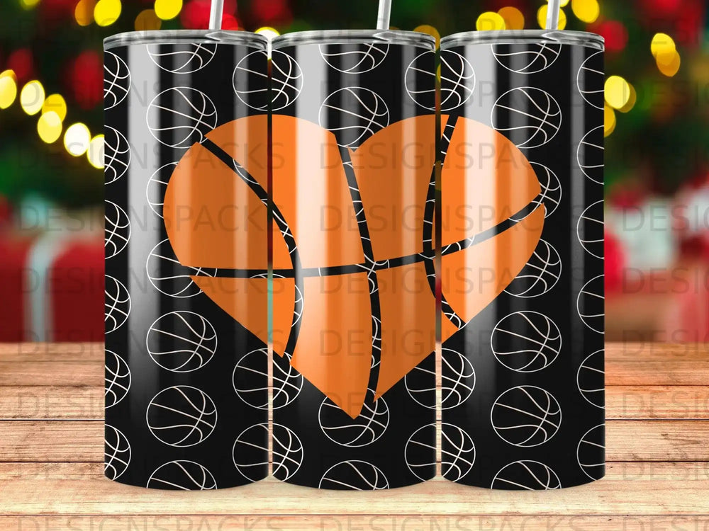 Black tumbler with repeating basketball heart pattern and holiday lights bokeh.