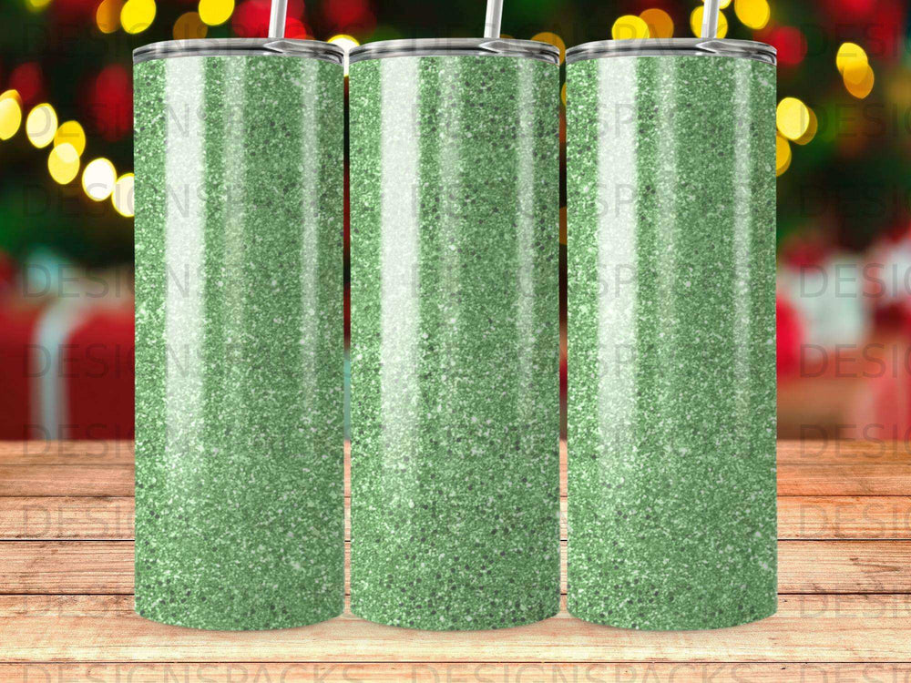Three glittery green tumblers with straws against a bokeh background.