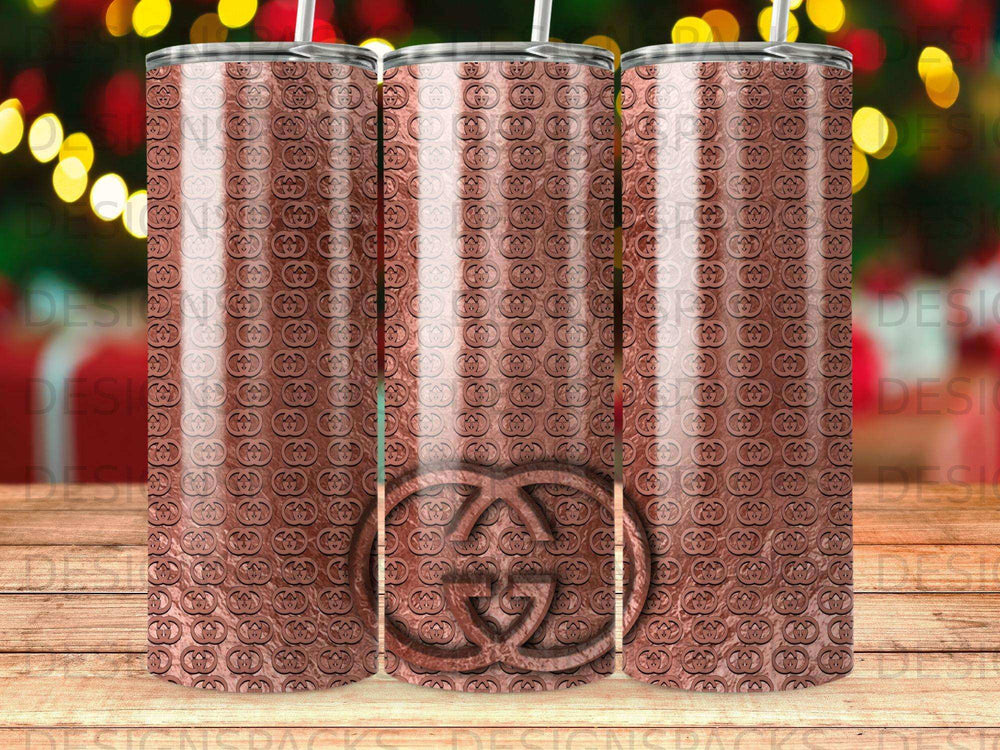 Three rose gold tumblers with repeating interlocking "G" logo pattern.