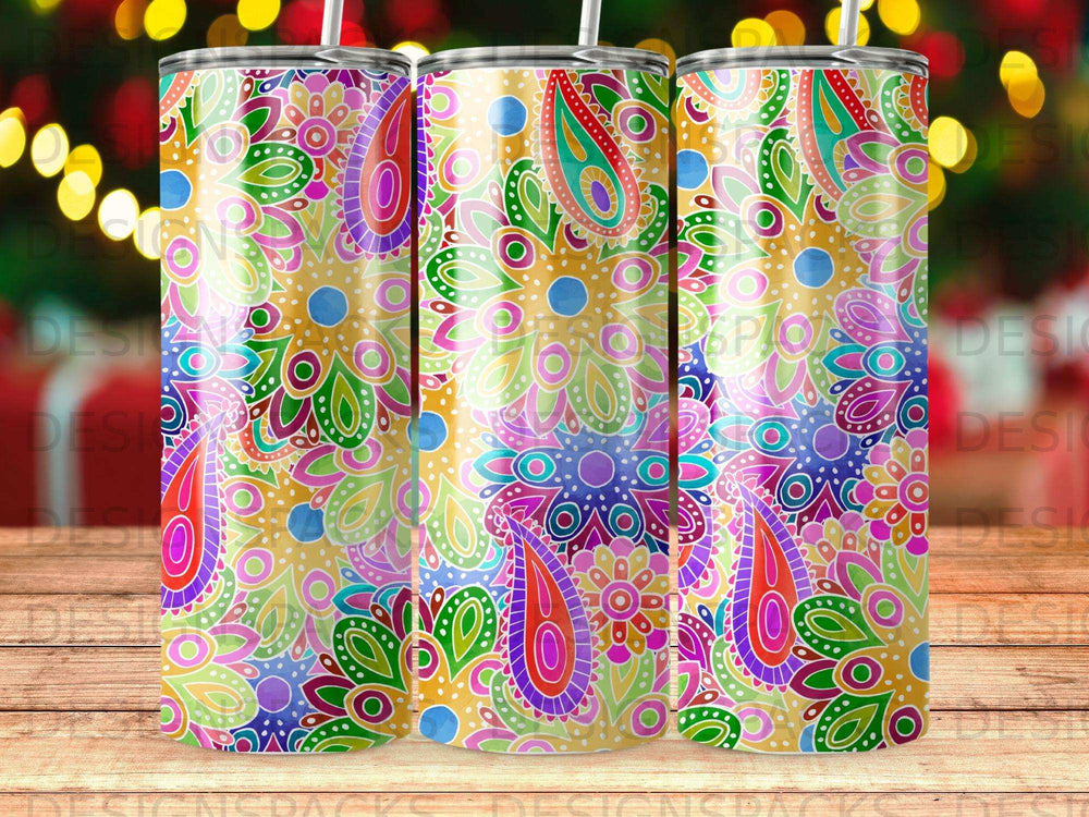 Three tumblers with colorful paisley floral patterns on a wooden surface.