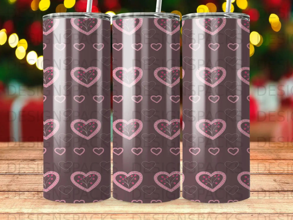 Tumbler with repeating pink heart pattern on a blurred background.