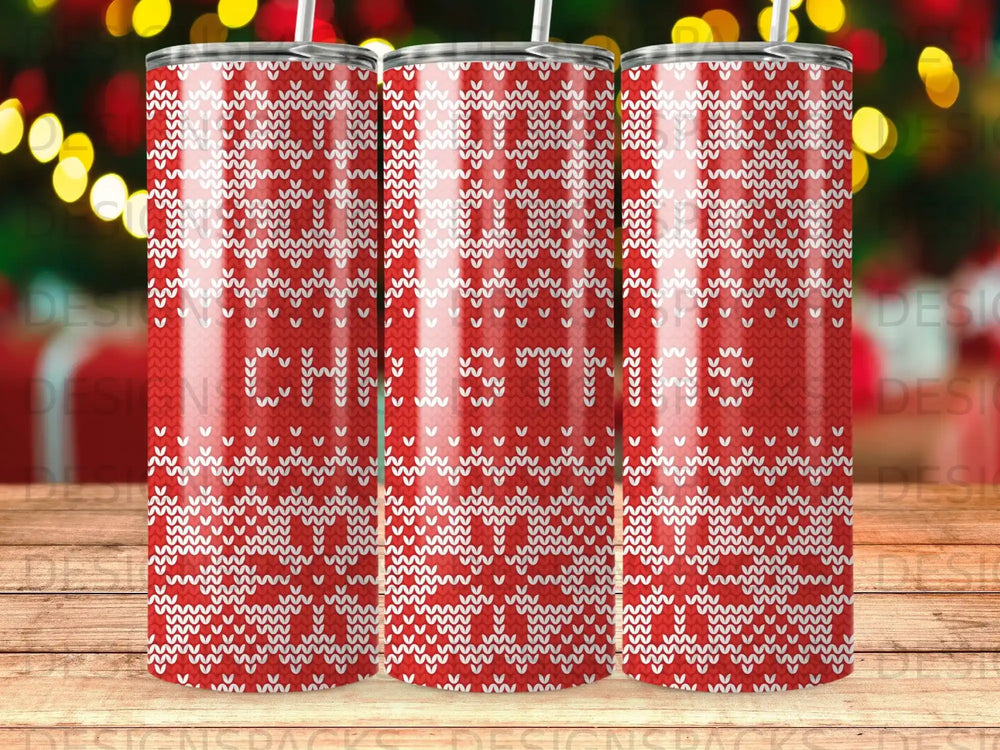Red tumbler with white knitted "CHRISTMAS" pattern and blurred bokeh background.