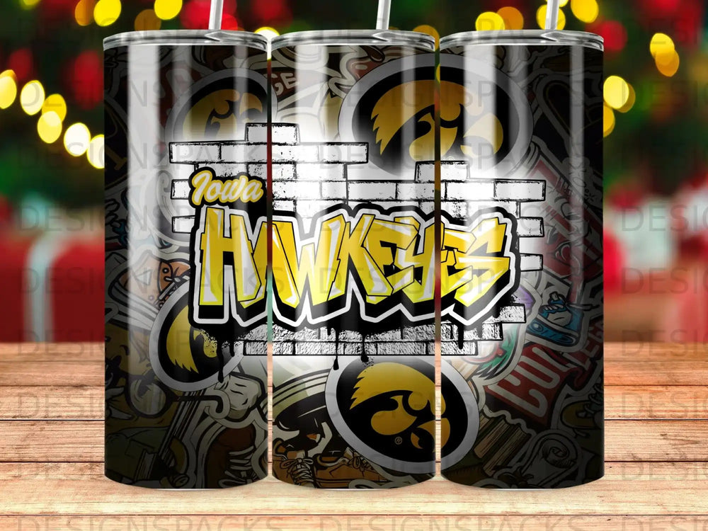 Iowa Hawkeyes graffiti-style logo on a tumbler with brick and sticker background.