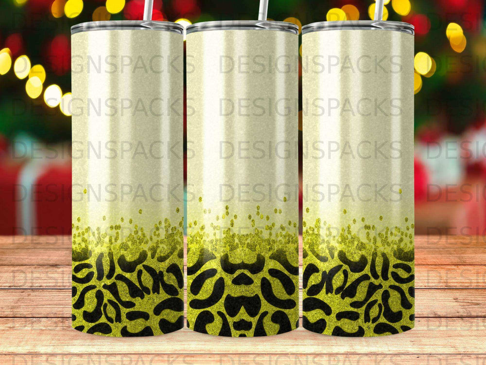 Three tumblers with leopard print and glitter designs on a wooden background.