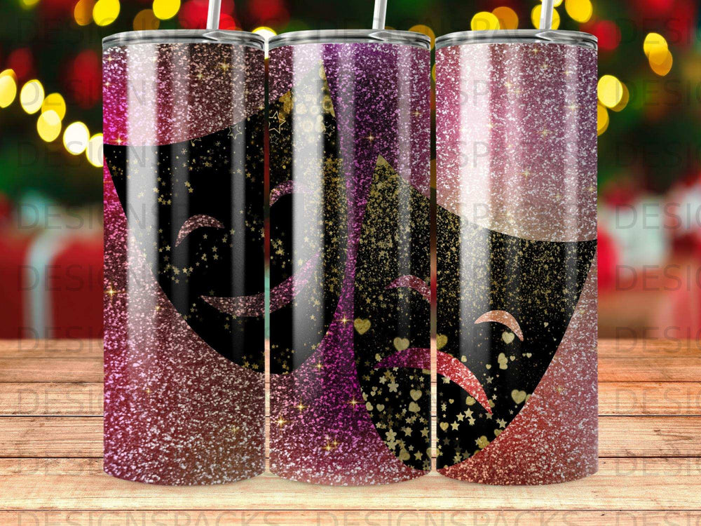 Three glitter-covered tumblers with theatrical masks and golden hearts.