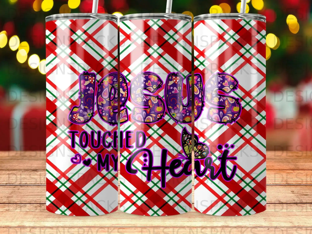 Tumbler with "JESUS TOUCHED MY HEART" in colorful lettering on plaid background.