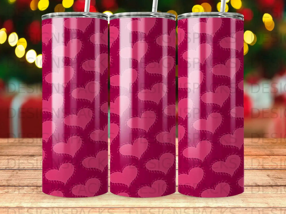 Three tumblers with a pink heart pattern on a dark red background.