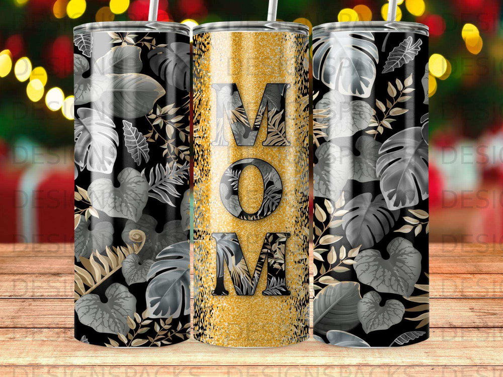 Three tumblers with "MOM" in gold glitter on a dark leaf pattern.