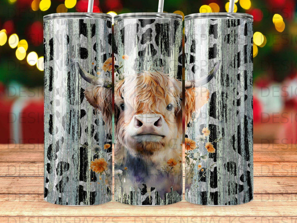 Highland cow with floral accents on a wood grain and cow print tumbler.