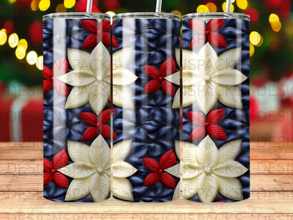 Three tumblers with a dark blue quilted background and repeating cream and red poinsettia floral pattern.