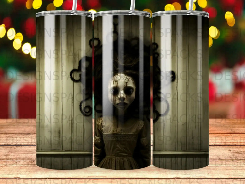 Creepy doll with cracked porcelain face and dark, messy hair on a tumbler.