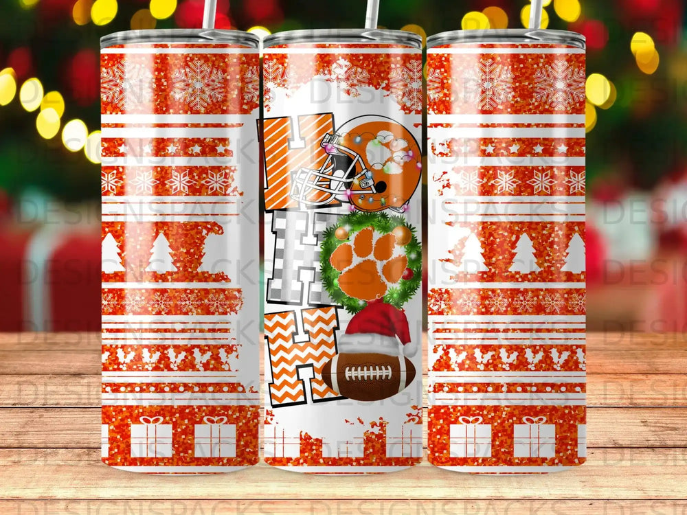Orange tumbler with white snowflakes and presents, "HO HO HO" text, football, and paw print.