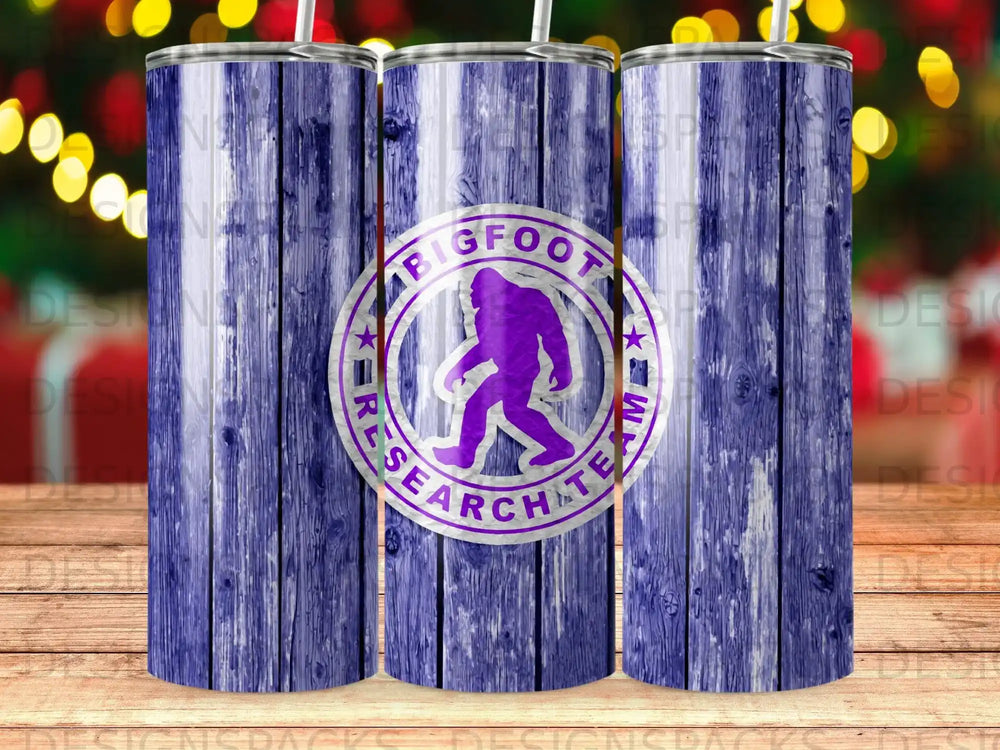 Purple Bigfoot research team logo on a wooden textured tumbler.