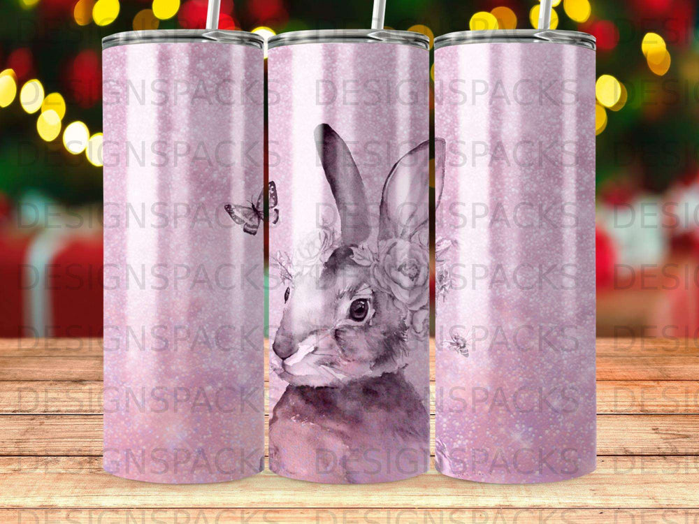Watercolor bunny with flowers on a pink tumbler, repeating "DESIGNSPACKS" pattern.