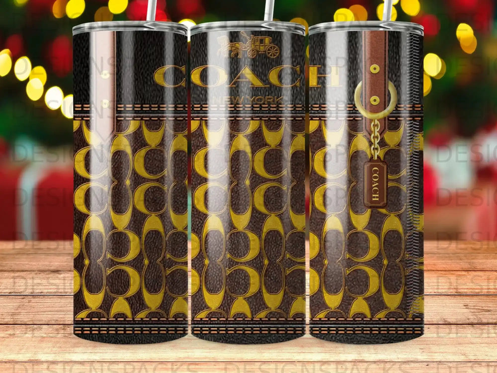 Coach New York monogram tumbler with gold hardware and brown leather tag.