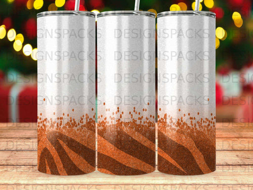 Three tumblers with orange glitter and tiger stripe designs on a wooden surface.