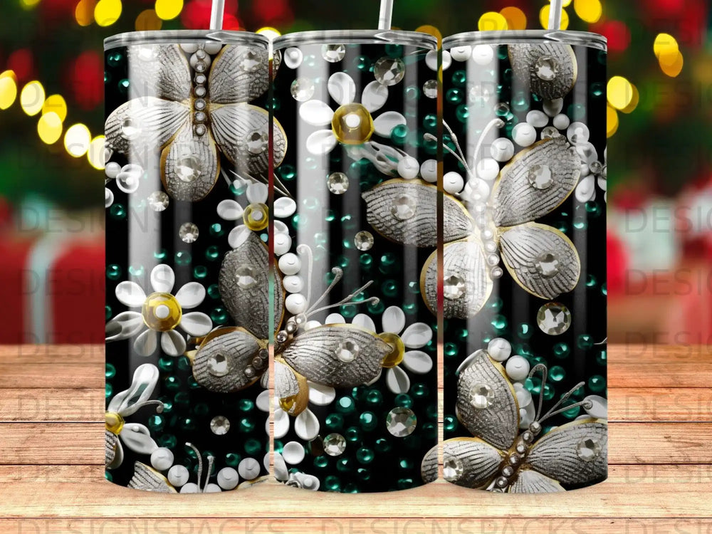 Tumbler with shimmering butterflies, white flowers, and green gems on a striped background.