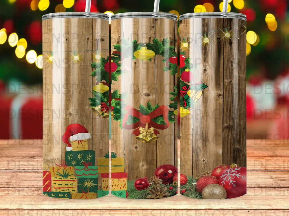 Christmas tumbler with gifts, ornaments, and a wreath on a wood background.