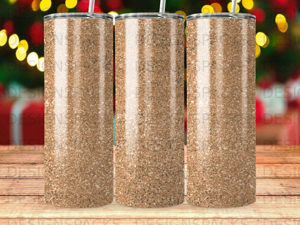 Three glittery gold tumblers with straws stand in a row.
