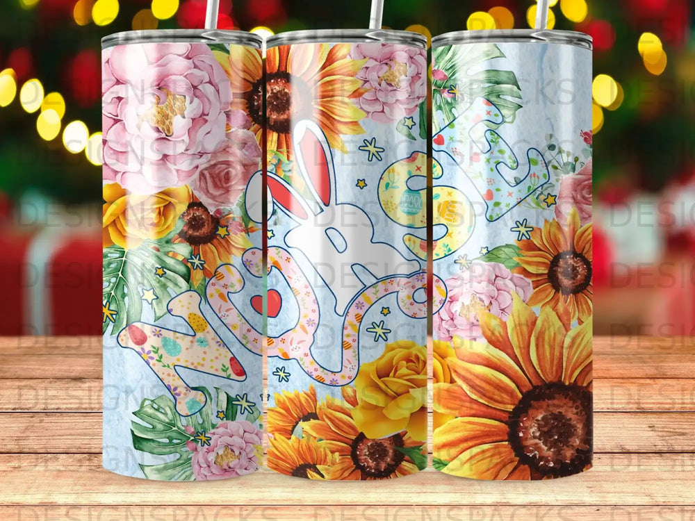Floral bunny design on three tumblers with blurred festive lights background.