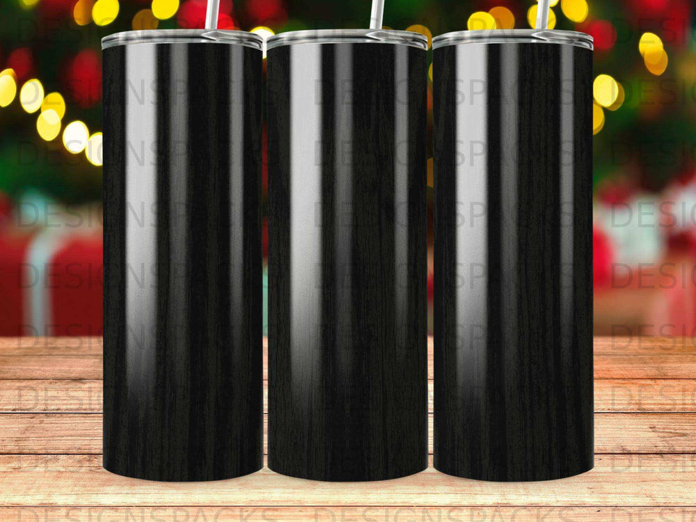 Three black wood grain tumblers with straws, blurred festive lights in background.