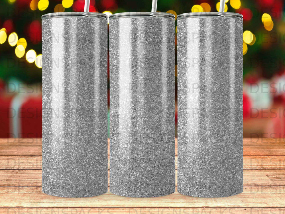 Three glitter-covered tumblers with straws against a bokeh background.
