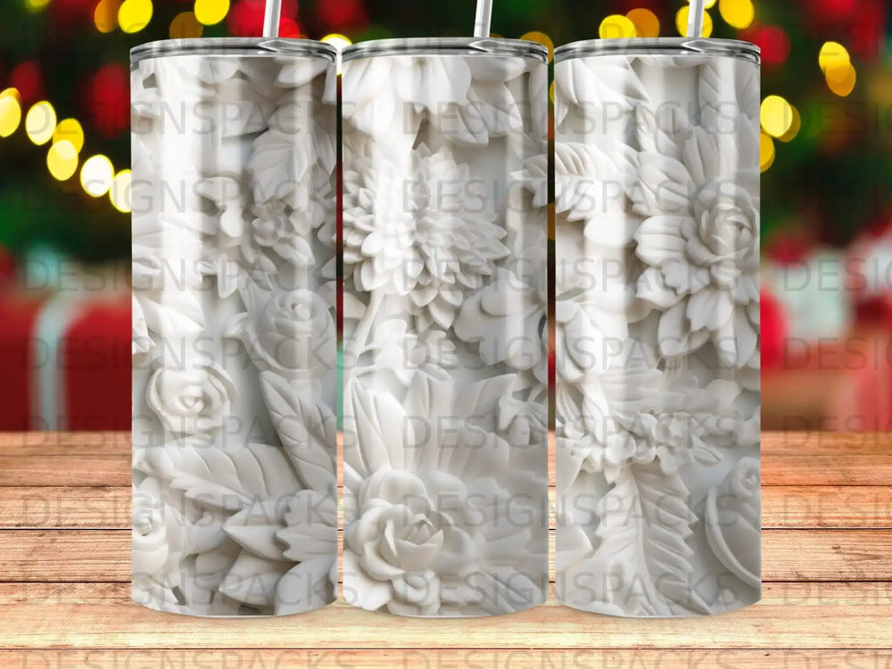 Three white tumblers with raised floral designs on a wooden surface.
