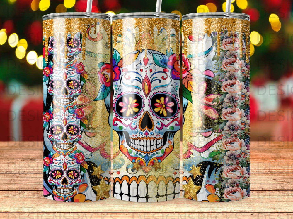 Three decorative sugar skulls with floral and glitter accents on a tumbler.