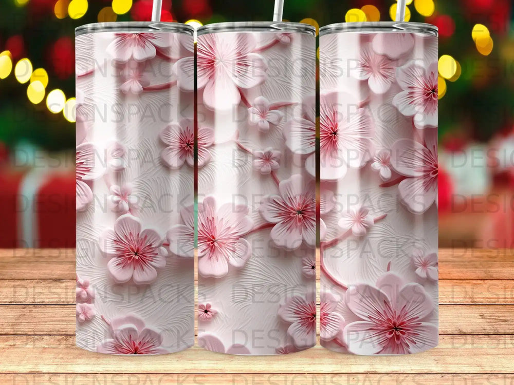 Three tumblers with a repeating pink floral pattern on a wooden background.