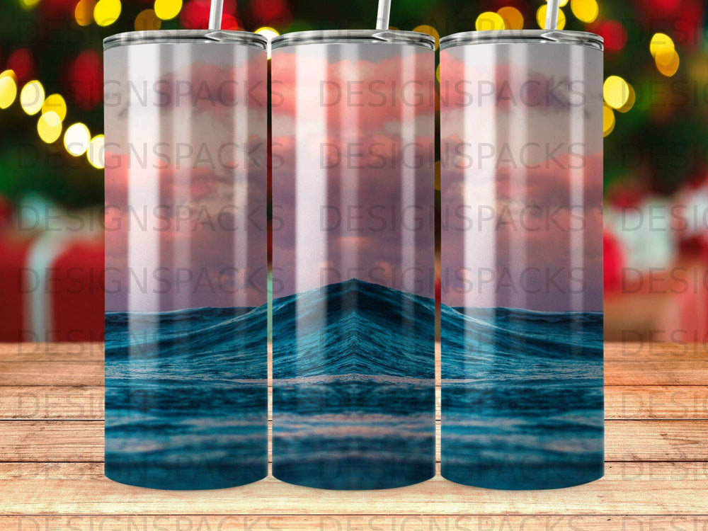 Three tumblers with a blue ocean wave design against a gradient sky.