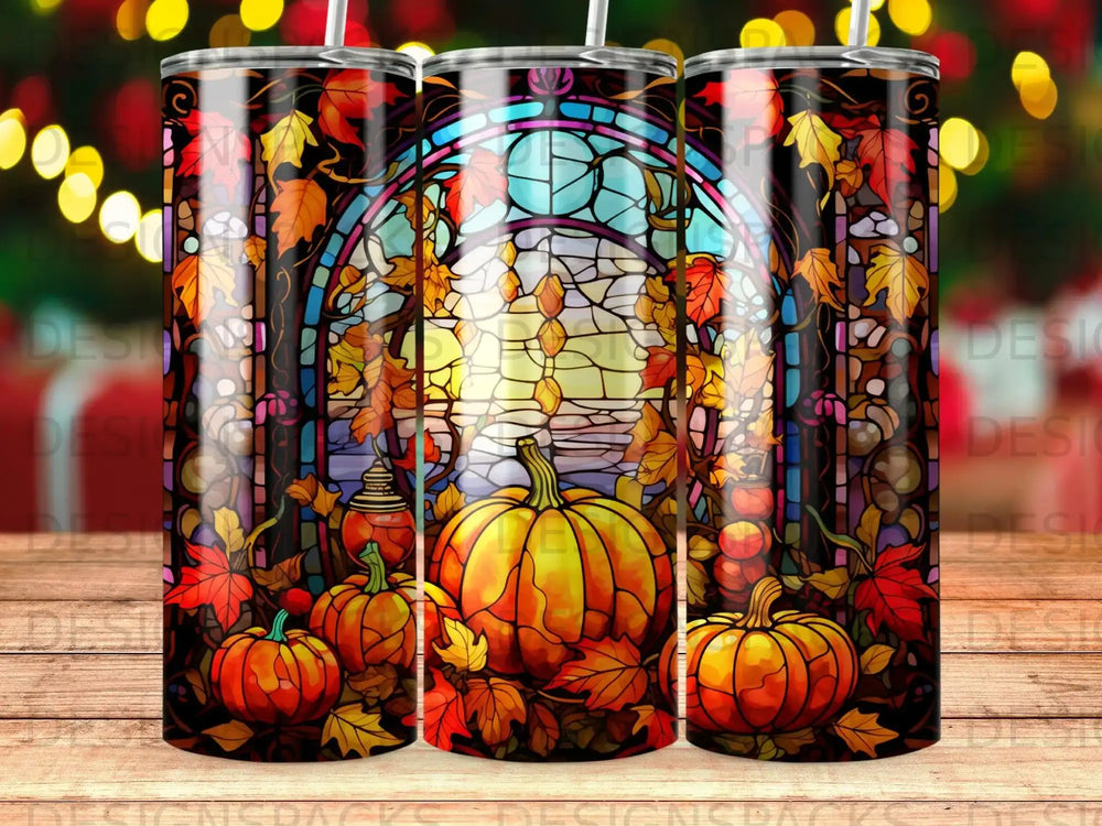 Three tumblers featuring pumpkins and autumn leaves against a stained-glass window.