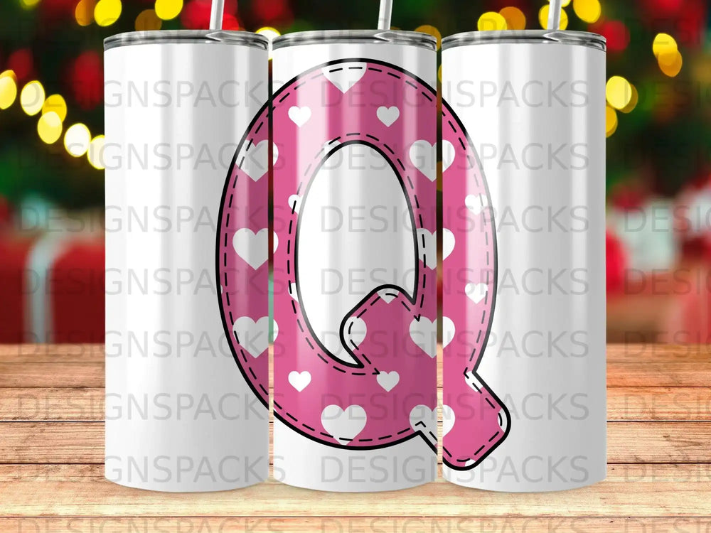 Pink tumbler with white hearts and a large white letter Q.