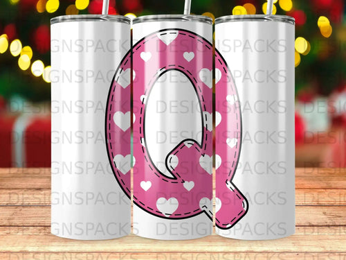 Pink tumbler with white hearts and a large white letter Q.