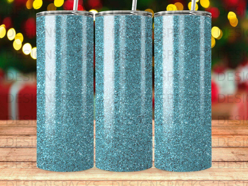 Three glittery blue tumblers with straw, blurred festive background.